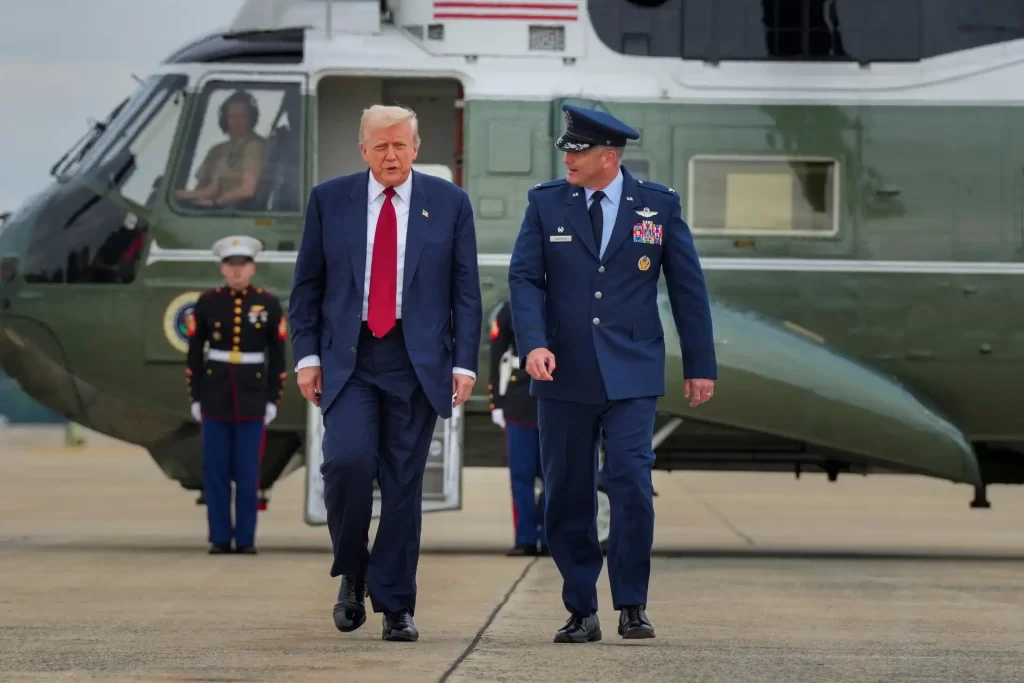 Imagem de Donald Trump e um oficial militar americano caminhando na pista de decolagem ao lado de uma aeronave militar, com crianças soldados ao fundo.