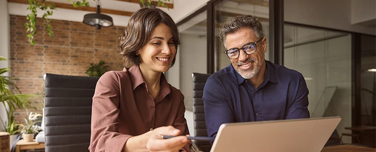 Dupla de profissionais sorrindo durante reunião de negócios em escritório moderno, usando laptop e tablet, promovendo colaboração e inovação, no dia do advogado