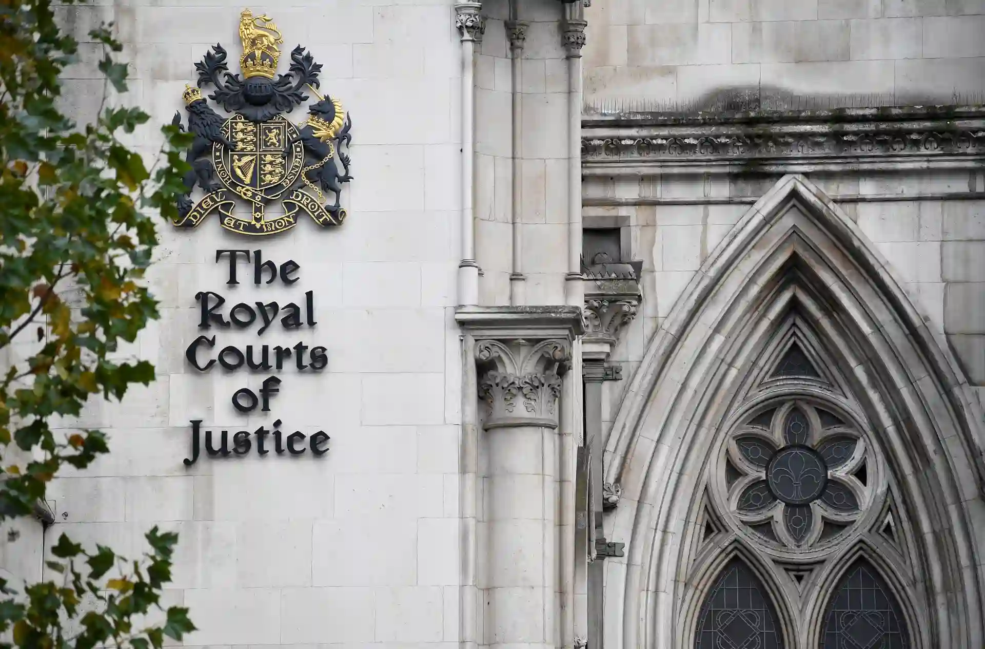 Fachada do edifício do Tribunal de Justiça Real do Reino Unido com o escudo da monarquia e aviso do nome do local em letras negras