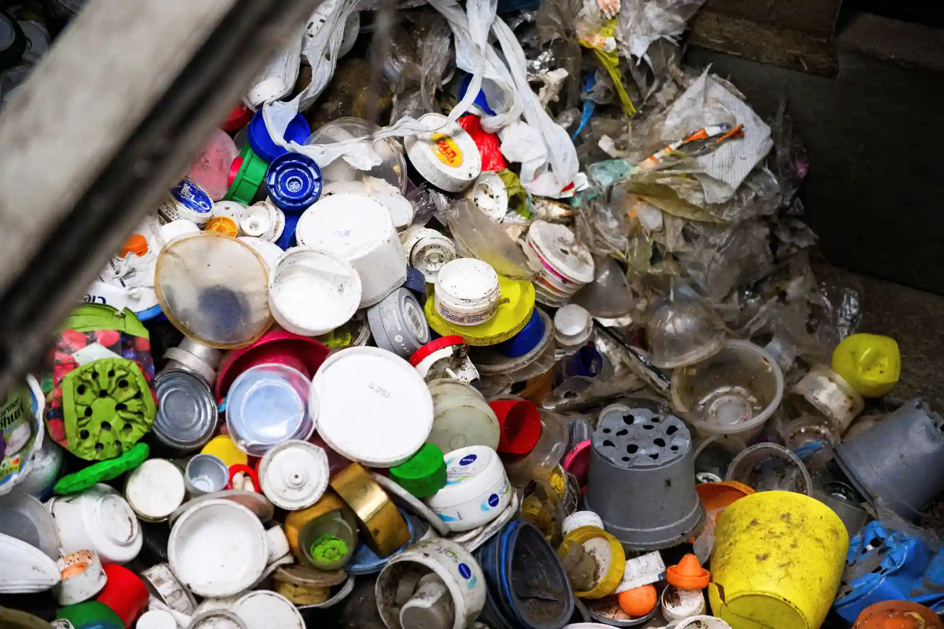 Imagem de lixo acumulado com diversos recipientes plásticos e materiais descartados em um ambiente de descarte irregular, demonstrando problemas ambientais causados pelo lixo doméstico.