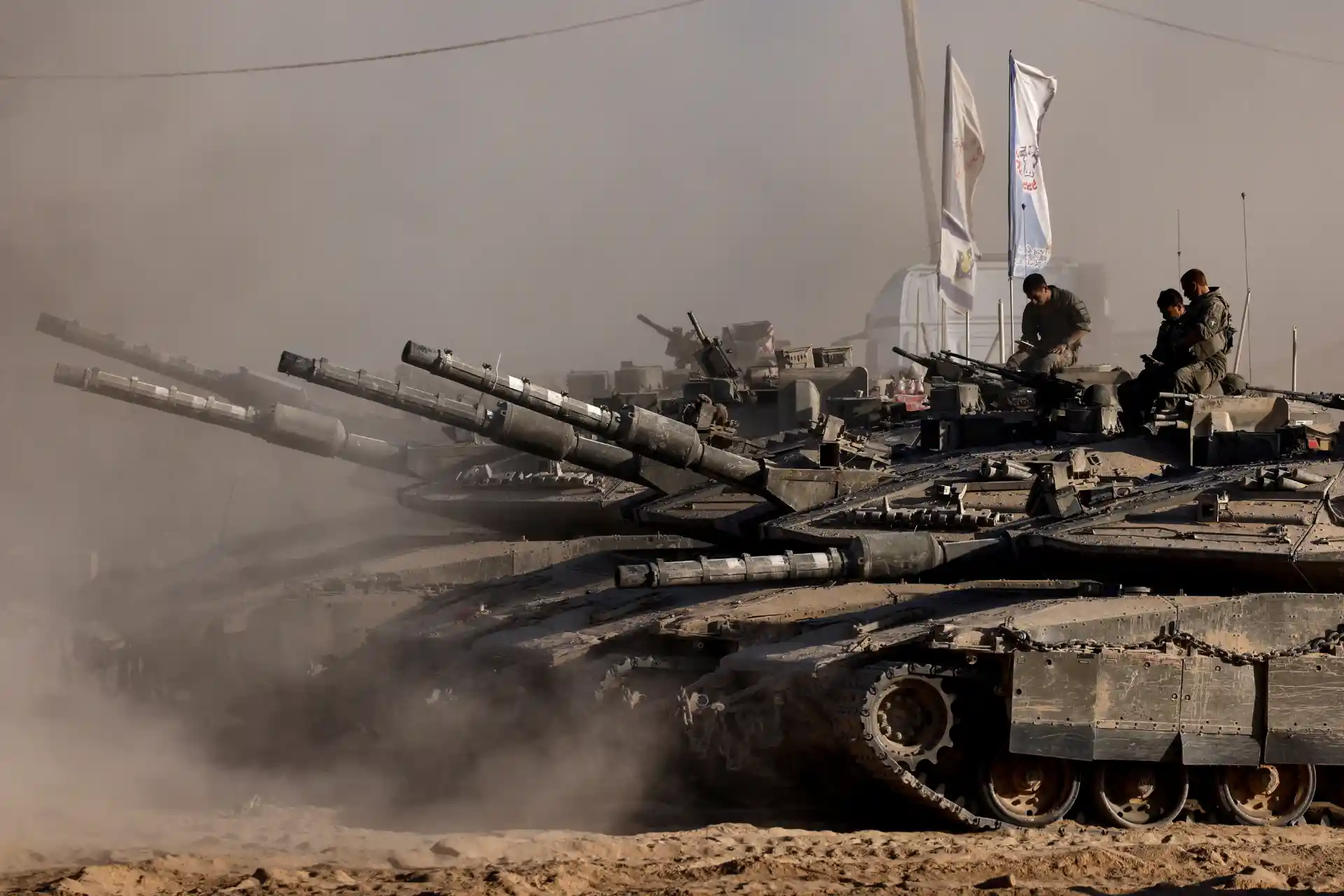 Tanques de guerra em operação de combate em um ambiente árido e com muita poeira,