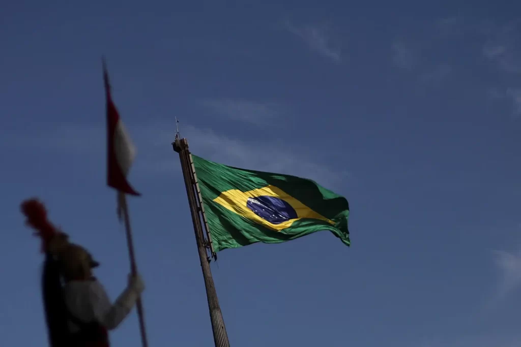 Governo brasileiro recebe com "profunda indignação" novas sanções dos EUA Bandeira do Brasil dobrada ao vento no céu azul, símbolo nacional em destaque, ideal para representar patriotismo e identidade brasileira.