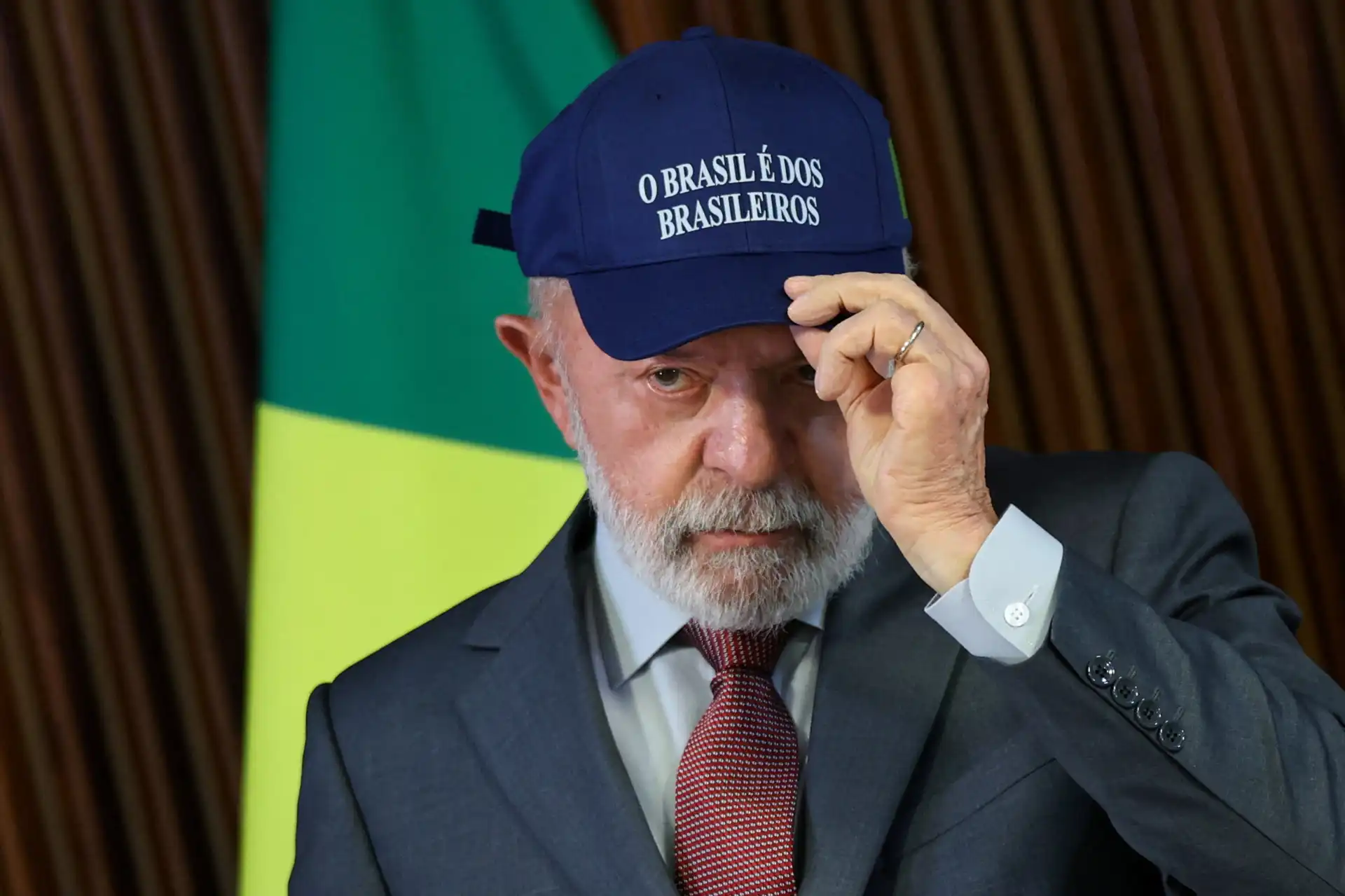Homem vestindo terno e gravata, usando boné com a frase 'O Brasil é dos brasileiros', símbolo de patriotismo e orgulho nacional.