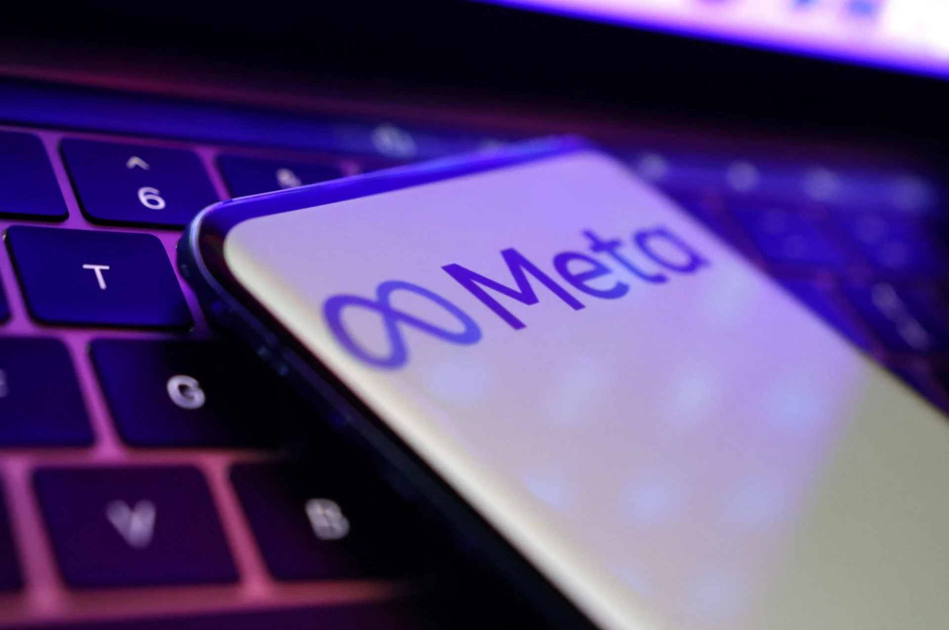 Smartphone mostrando o logo do aplicativo Meta em uma superfície de teclado, com foco na tela e iluminação moderna.