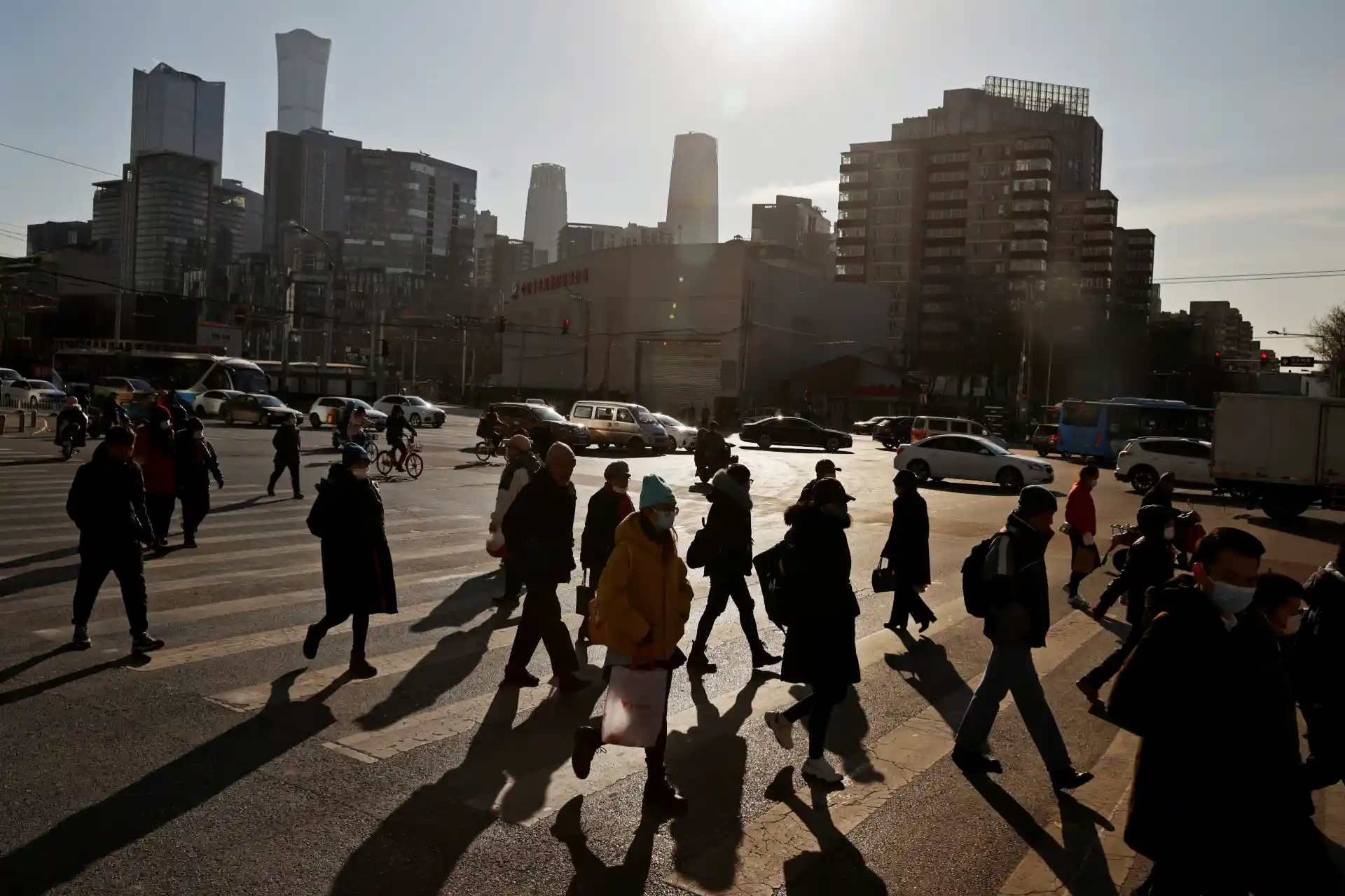 Imagem de uma movimentada rua de uma cidade grande com pedestres atravessando a faixa de pedestres e arranha-céus ao fundo, refletindo o movimento urbano.