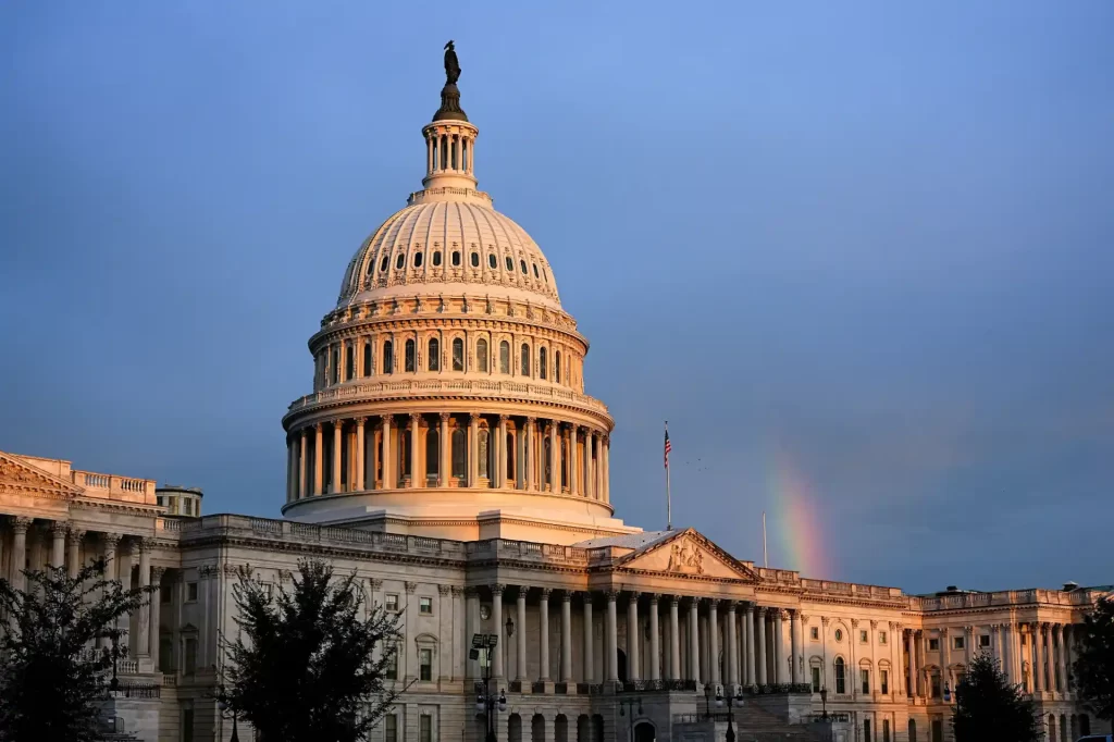 Imagem da Casa Branca em Washington, com nuvens no céu e um arco-íris ao fundo, simbolizando o símbolo emblemático de Washington, DC, Estados Unidos.
