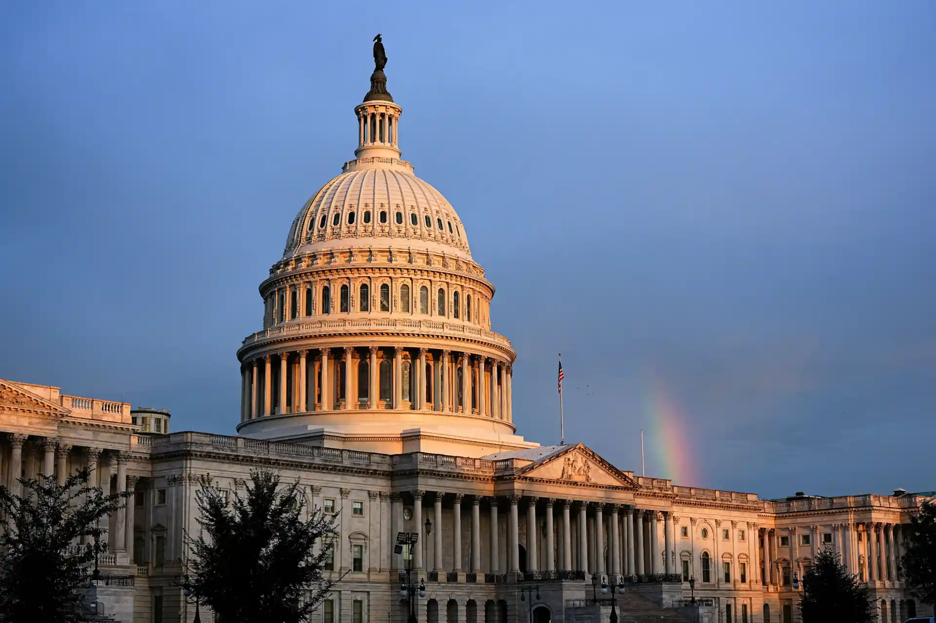 Imagem da Casa Branca em Washington, com nuvens no céu e um arco-íris ao fundo, simbolizando o símbolo emblemático de Washington, DC, Estados Unidos.
