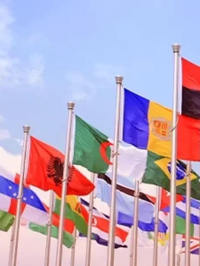 Bandeiras de vários países de diferentes continentes ao vento, simbolizando união internacional e diversidade cultural.