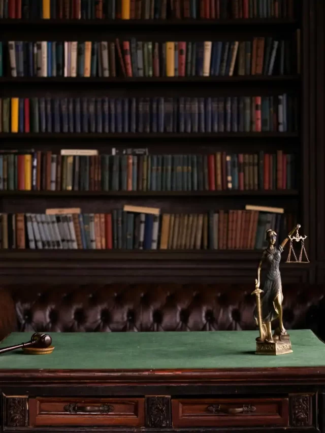 Story Sala de reuniões clássica com móveis de madeira, estante cheia de livros e um símbolo de justiça na mesa, transmitindo um ambiente de profissionalismo e elegância.
