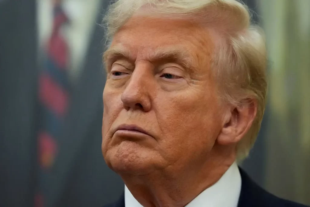 Imagem de Donald Trump, expressando uma expressão séria e pensativa, vestindo terno em ambiente de fundo desfocado. Fotografia de alta qualidade.