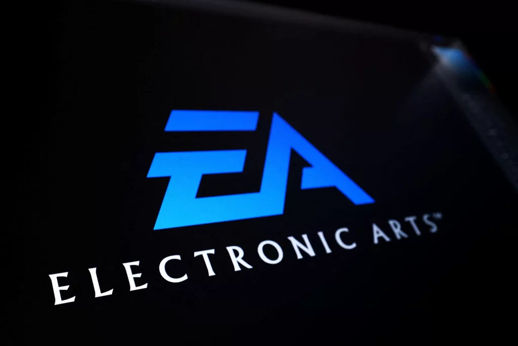 Logotipo da Electronic Arts exibido em um fundo escuro, com destaque para o símbolo azul e o nome 'Electronic Arts' em branco, representando uma empresa de jogos eletrônicos.