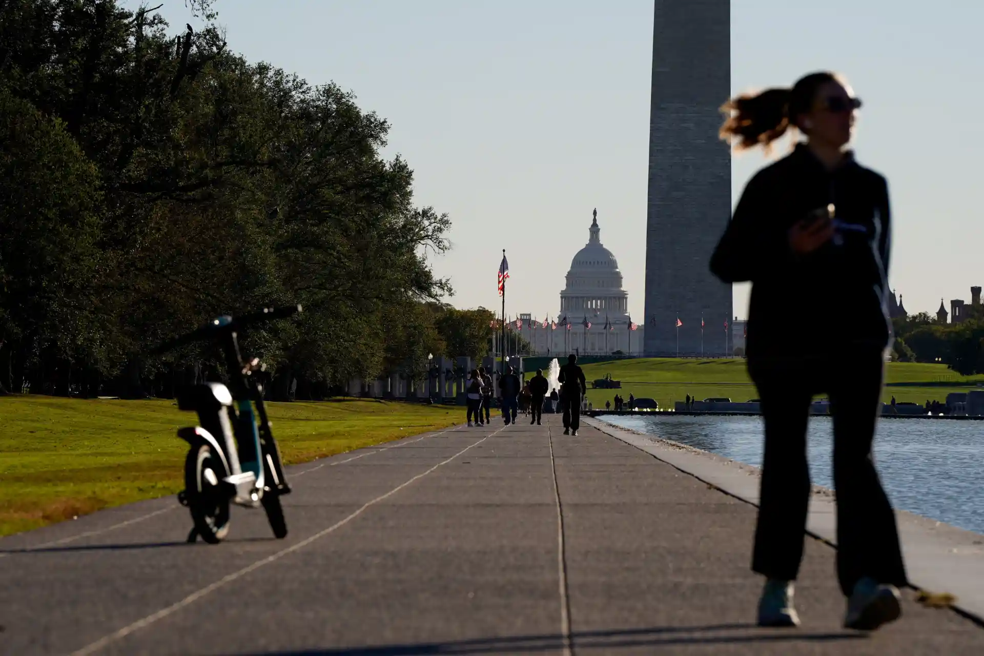 Pessoa caminhando ao longo do National Mall em Washington, D.C., com vista para o Capitólio e Lincoln Memorial ao fundo.