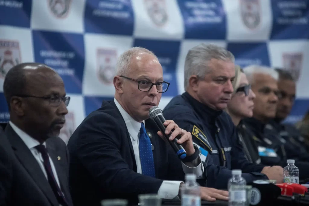 Reunião de autoridades de segurança, incluindo policiais e representantes institucionais, em evento de segurança pública, com destaque para o homem ao centro falando ao microfone.