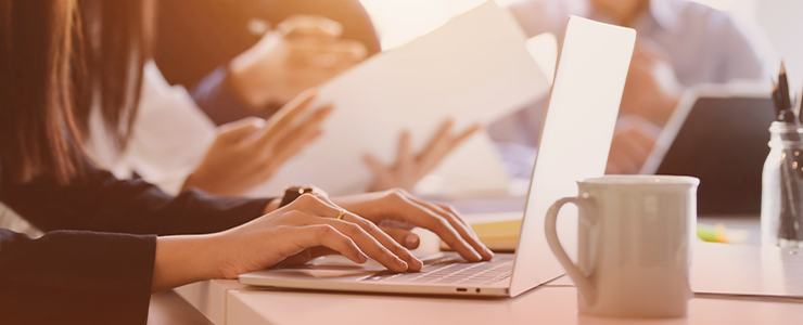 Pessoas trabalhando de perto em um ambiente de escritório, usando laptops e tablets para tarefas de trabalho, com foco na colaboração e produtividade e Direito Constitucional do Trabalho