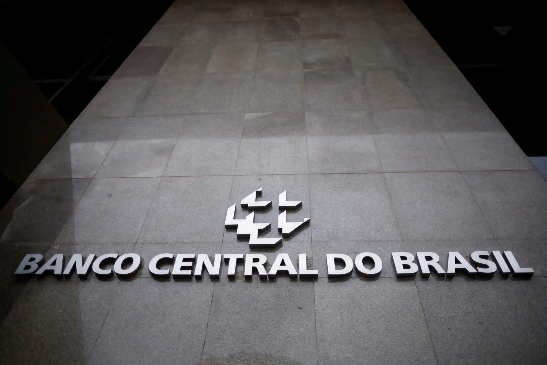 Fachada do Banco Central do Brasil com o logo em destaque na parede de pedra cinza.