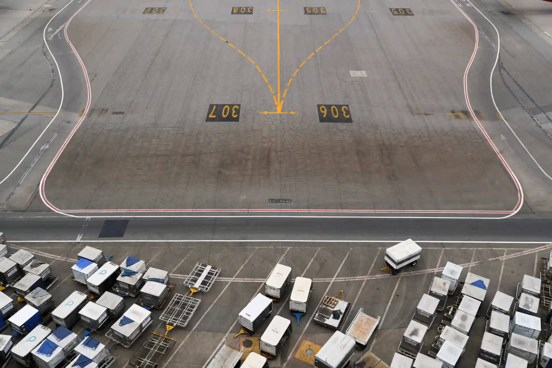 Estacionamento de veículos no aeroporto, com marcas de sinalização e linha de pista, incluindo áreas reservadas para vans e outros veículos.