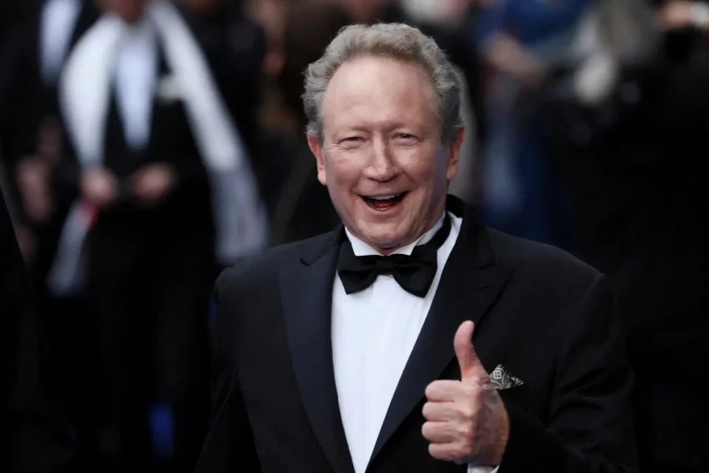 Homem sorridente em traje formal com terno e gravata e fazendo sinal de positivo em evento social.