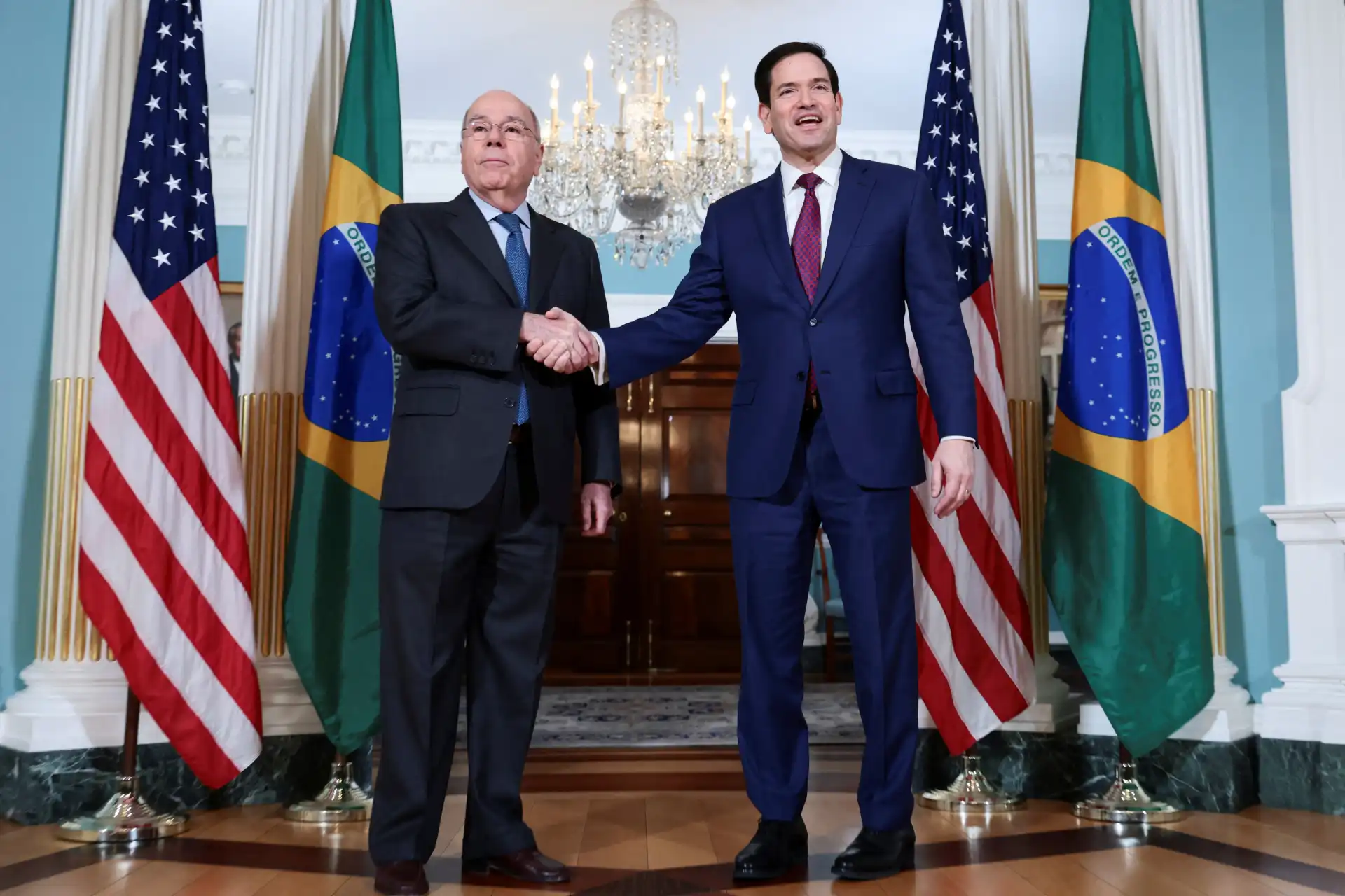 Lula e Joe Biden se cumprimentando durante reunião oficial, simbolizando parceria entre Brasil e EUA, com bandeiras de ambos os países ao fundo e decoração elegante.