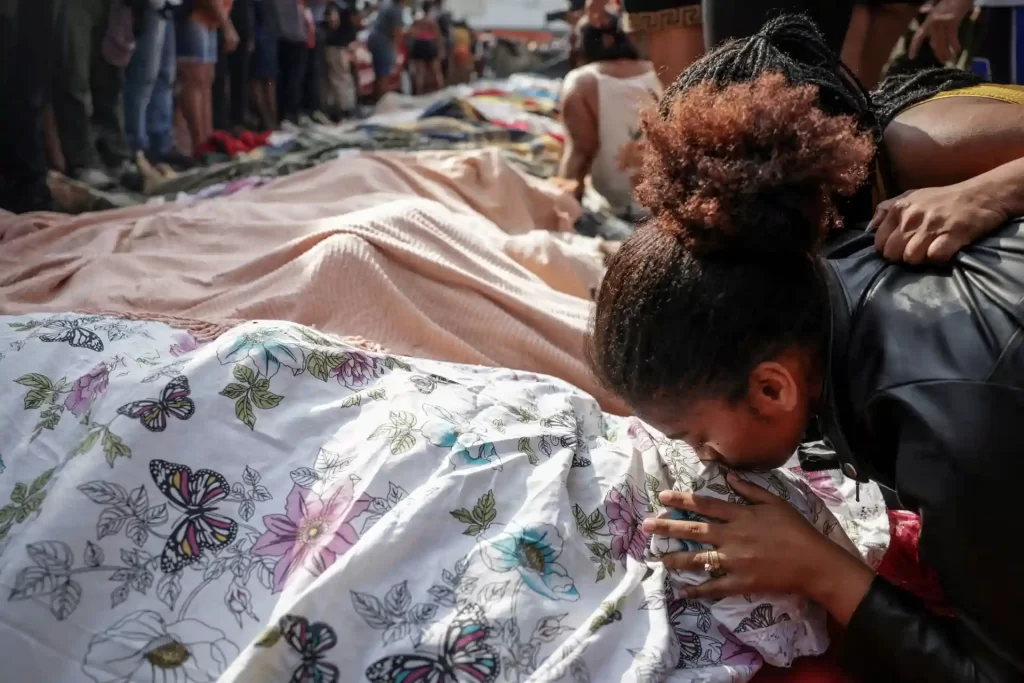 Mulher emocionada diante de um mosaico de flores e borboletas, no momento de oração ou despedida com objetos de uma cerimônia de despedida.