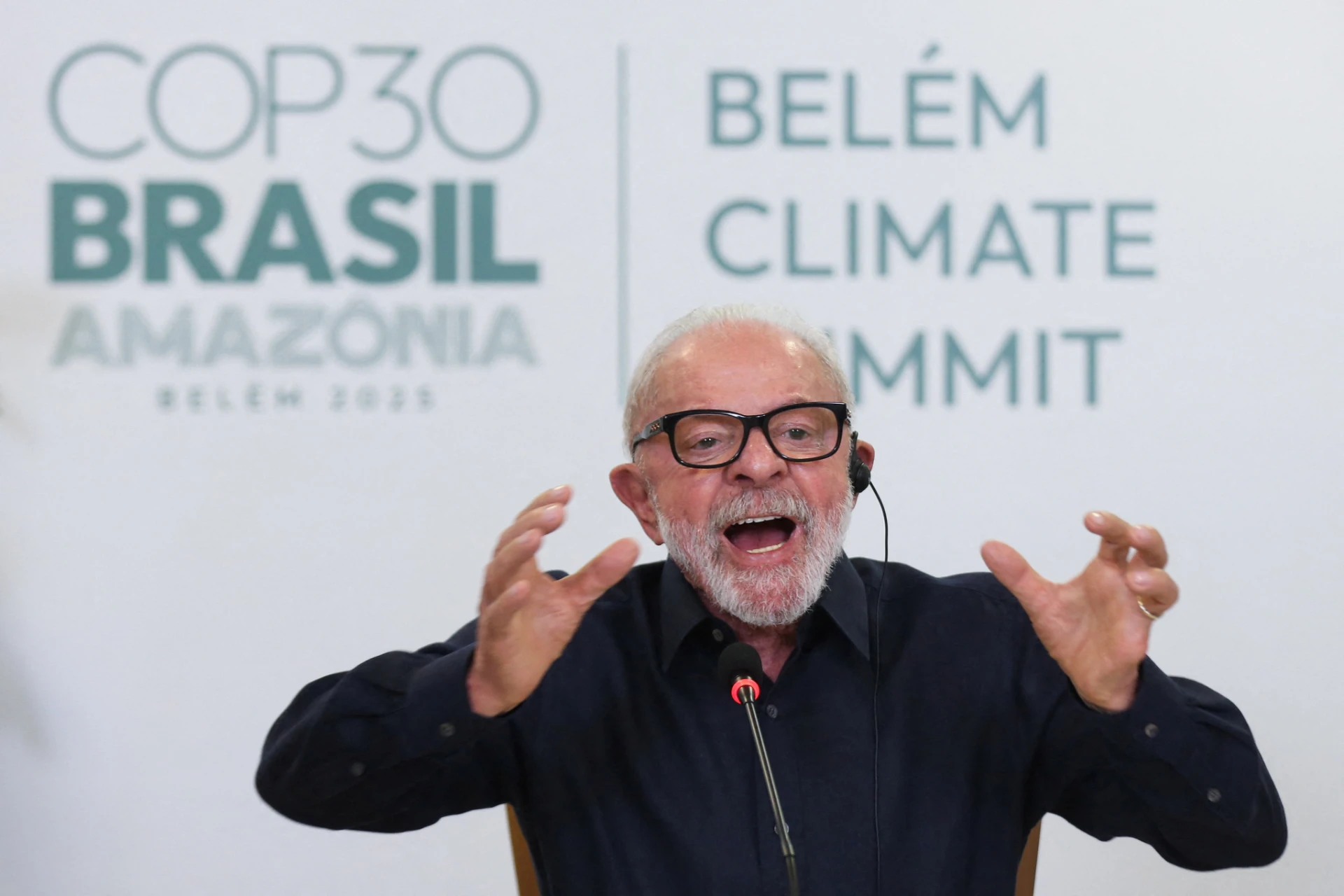 Palestrante falando apaixonadamente na Conferência sobre o Clima na Amazônia, durante o Clima Summit em Belém, com o logo do evento ao fundo.