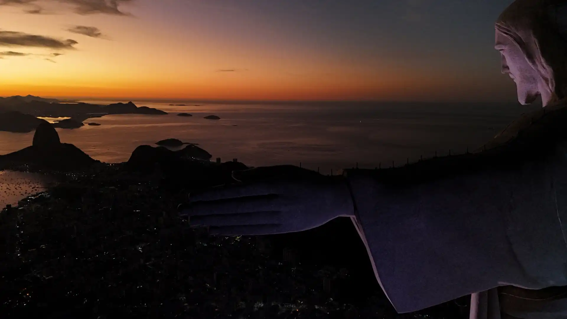Pessoa observando o pôr do sol na praia ao entardecer, com o mar e o céu coloridos no horizonte. Cena tranquila e relaxante ao ar livre.