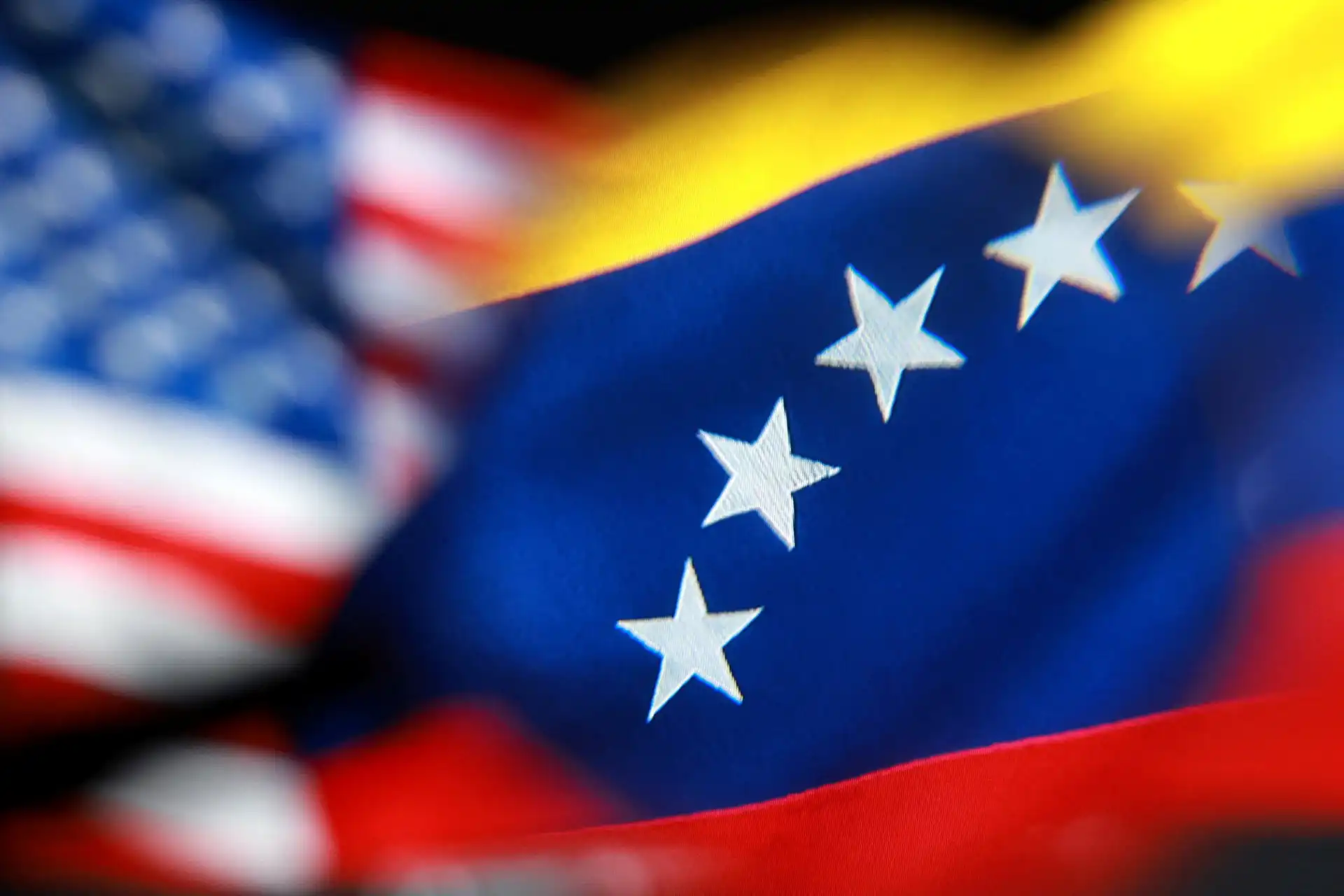 Bandeira dos Estados Unidos com destaque para as estrelas brancas em um fundo azul e elementos em vermelho e branco ao fundo, simbolizando patriotismo e orgulho nacional.