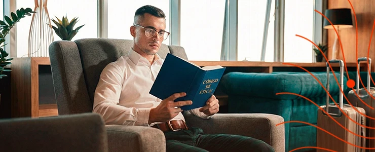 Homem lendo um livro sobre ética em um ambiente moderno, transmitindo reflexão e estudo sobre comportamento ético no contexto corporativo. Código de ética