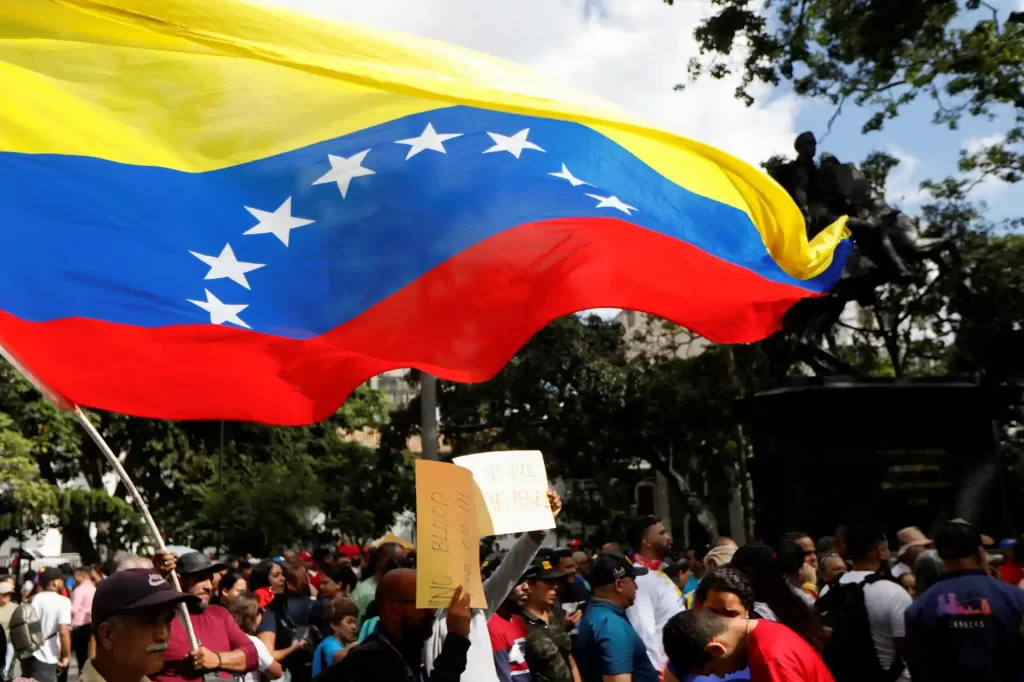 Manifestantes durante protesto segurando a bandeira nacional da Venezuela em uma manifestação ao ar livre