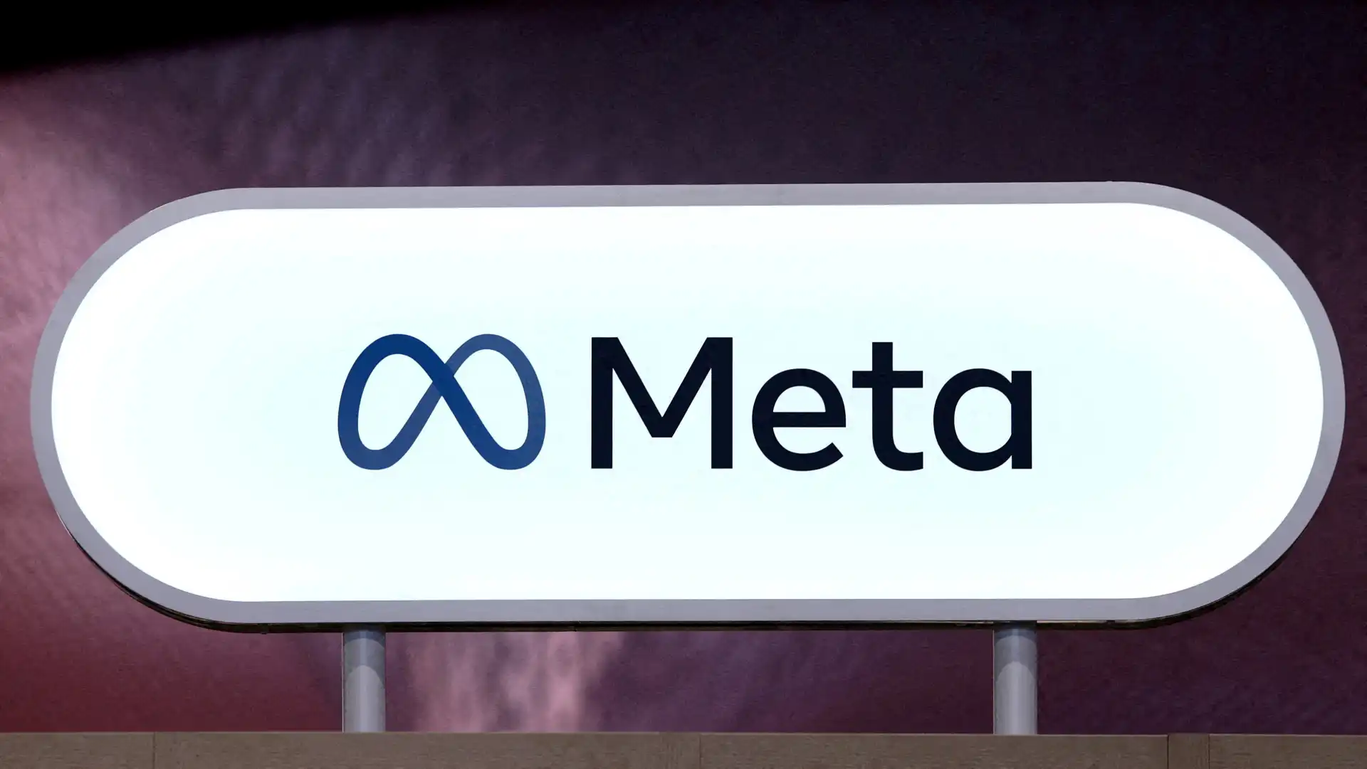 Imagem de um outdoor com o logo do Meta, a gigante de tecnologia dona do Facebook, Instagram e WhatsApp, com fundo escuro e foco no logo e nome 'Meta'