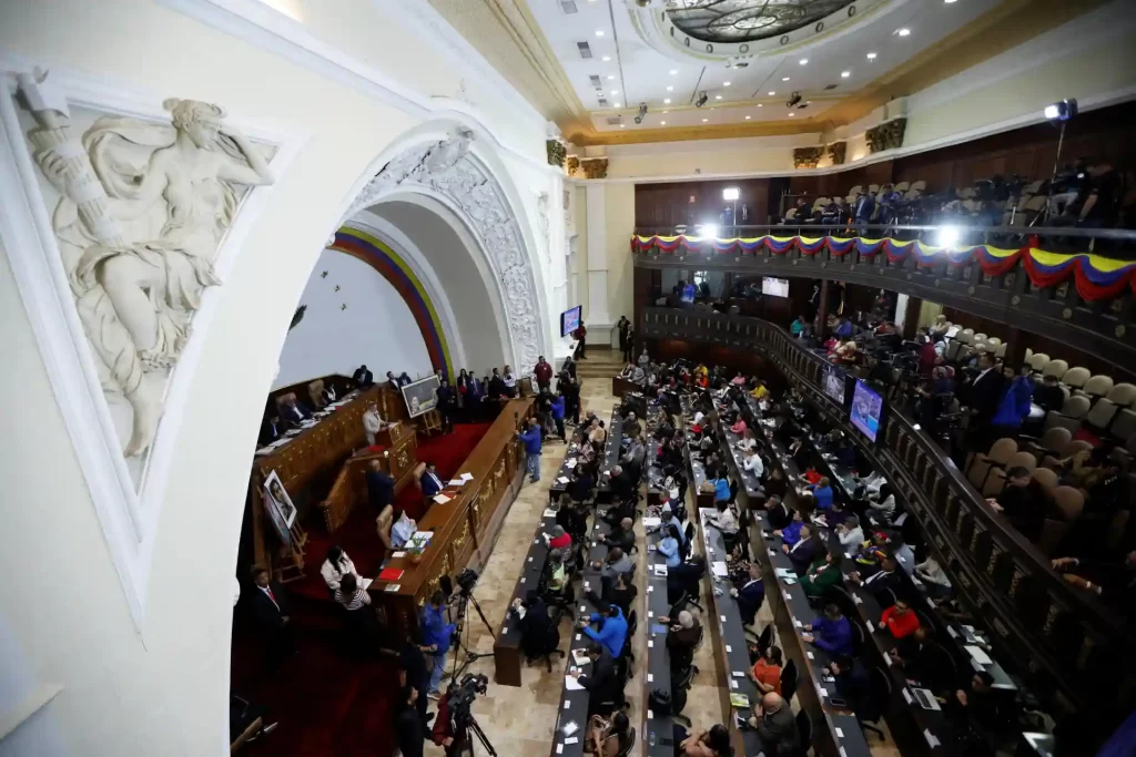 Sessão do Parlamento Nacional na cerimônia oficial, com deputados e autoridades presentes no plenário, decorado com bandeiras e detalhes arquitetônicos tradicionais.
