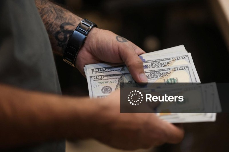 Homem conta notas de dólar 05/10/2025. Majid Asgaripour/WANA (West Asia News Agency) via REUTERS