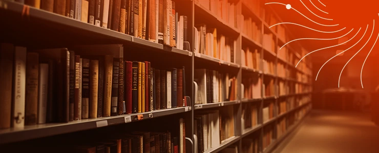 Estantes de uma biblioteca com livros organizados e iluminação suave, criando um ambiente acolhedor para leitura e pesquisa.