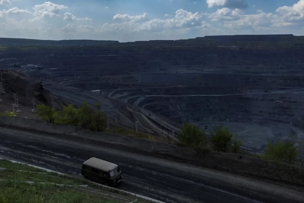 Imagem de uma mina a céu aberto com áreas de escavação e transporte de minerais, refletindo a atividade de mineração industrial.