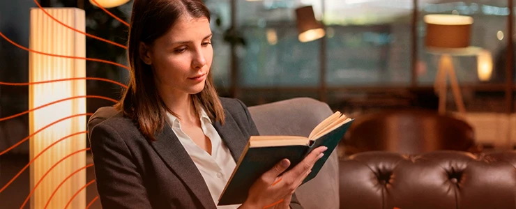 Mulher lendo um livro em ambiente aconchegante com iluminação suave, cadeira de couro e decoração moderna, ideal para quem gosta de leitura e relaxamento. tributária