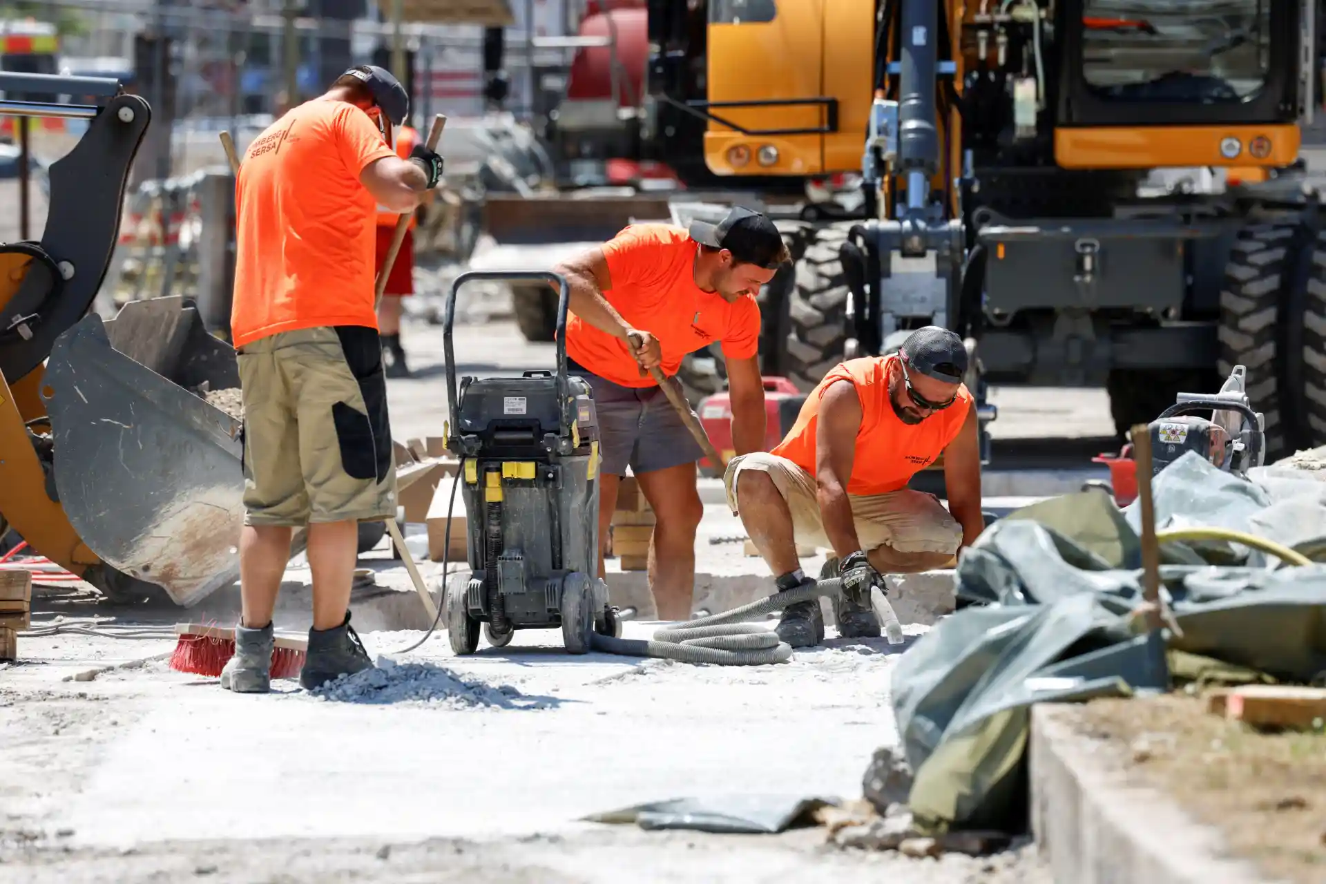 Trabalhadores construindo asfalto na rua com equipamentos e máquinas, cenário de obra de pavimentação urbana.