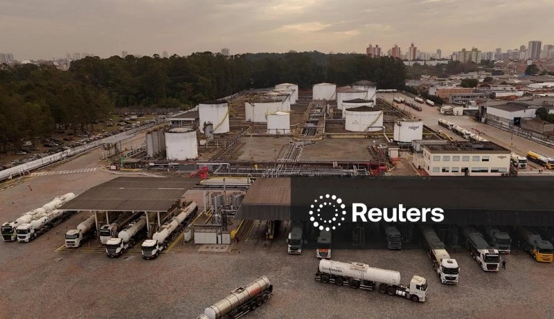 Imagem de uma usina industrial com tanques, caminhões e infraestrutura tecnológica ao fundo, ilustrando setor de energia ou petróleo.